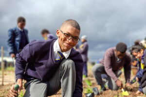 Student planting indigenous vegetation as part of a community-led habitat restoration initiative in South Africa.